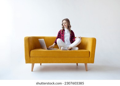 jovencita linda usa laptop con cómodo sofá suave, tipos de mujeres en línea en el ordenador en sofá amarillo con fondo blanco aislado