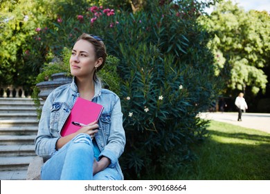 Young Cute Hipster Girl Is Enjoying Beautiful Day And Recreation Time During Her Spring Vacation Overseas, Pretty Female Is Dreaming About Something Good While Is Sitting Outdoors In Beauty Green Park