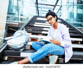 young cute indian girl at university building sitting on stairs 