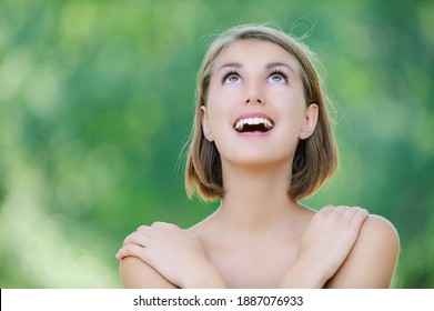 Junge süße lachtige Frau schaut im Sommerpark auf.