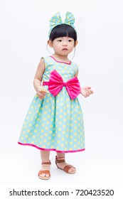 Young Cute And Lovely Little Korean Girl (or Little Kid) Wearing Green Blue (or Soft Blue) Dress With Polka Dot Pattern And Belting Red Bow (like A Korean Hanbok) Standing On White Background