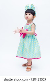 Young Cute And Lovely Little Korean Girl (or Little Kid) Wearing Green Blue (or Soft Blue) Dress With Polka Dot Pattern And Belting Red Bow (like A Korean Hanbok) Standing On White Background