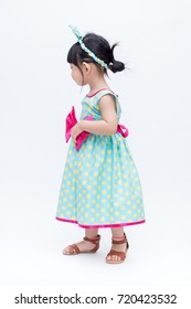 Young Cute And Lovely Little Korean Girl (or Little Kid) Wearing Green Blue (or Soft Blue) Dress With Polka Dot Pattern And Belting Red Bow (like A Korean Hanbok) Standing On White Background