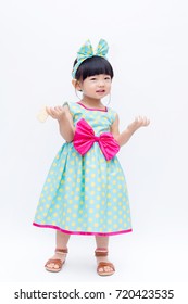 Young Cute And Lovely Little Korean Girl (or Little Kid) Wearing Green Blue (or Soft Blue) Dress With Polka Dot Pattern And Belting Red Bow (like A Korean Hanbok) Standing On White Background