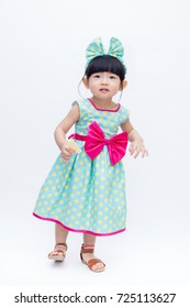 Young Cute And Lovely Little Korean Girl (or Little Kid) Wearing Green Blue (or Soft Blue) Dress With Polka Dot Pattern And Belting Red Bow (like A Korean Hanbok) Standing On White Background