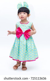 Young Cute And Lovely Little Korean Girl (or Little Kid) Wearing Green Blue (or Soft Blue) Dress With Polka Dot Pattern And Belting Red Bow (like A Korean Hanbok) Standing On White Background