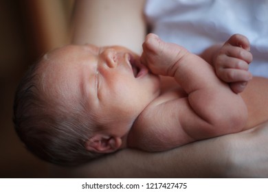 Young cute mother holding sleeping newborn son in her arms. Clouse up. The concept of a happy childhood, motherhood, breastfeeding.