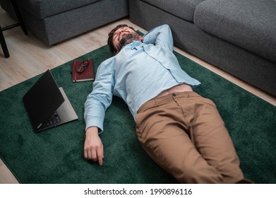 Young Cute Office Worker Lies On The Floor Mat Next To The Sofa, He Is Tired And Asleep, Top View