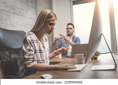Young cute pensive female freelance working on a new project at the office. She is looking at project on a computer. - Shutterstock ID 1239959503