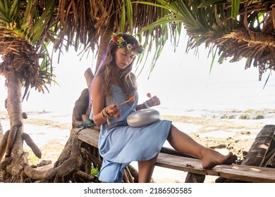 Young Cute Woman Meditation On Tropical Beach And Playing Hapi Steel Tongue Drum. Happy Female In Summer Clothes Resting At Seascape Play Relaxing Music. Summer Tropical Vacation, Travel Holiday