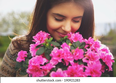 Young cute woman smelling pink flowers