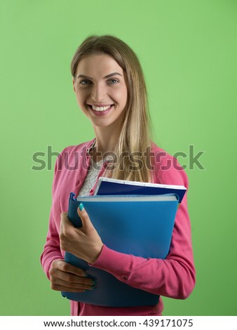 Young cute woman standing holding folder, green background