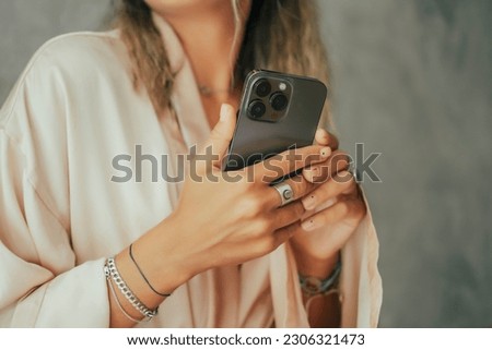young cute woman using phone,sitting at a cafe holding a smartphone,answering texts,phone calls,letters,posts photos in instagram,outdoor portrait, close up, elaborated and bracelets on the hands Imagine de stoc © 