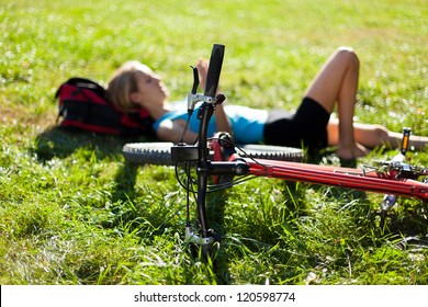 Young cyclist enjoying relaxation lying in the fresh green grass illuminated by the rays of sunlight. Outdoor