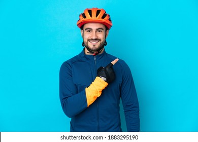 Young Cyclist Man Isolated On Blue Background Pointing To The Side To Present A Product