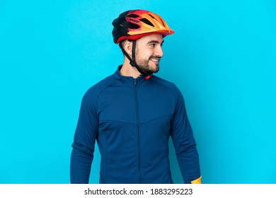 Young Cyclist Man Isolated On Blue Background Looking Side