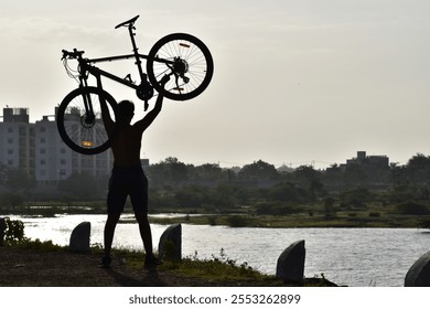 A young cyclist riding a mountain bike along a dirt path by a serene lake, representing an active lifestyle and outdoor exploration. - Powered by Shutterstock