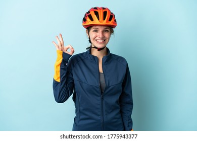 Young cyclist woman isolated on blue background showing ok sign with fingers