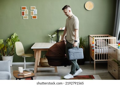 Young Dad Carrying Cradle From Pram And Bag In The Room, He Taking His Newborn Baby To Walk Outdoors