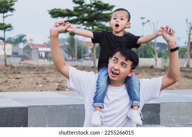 Young dad carrying son on shoulder at the park, little boy feel shocked.  - Shutterstock ID 2255266015