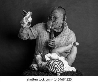 Young Dad Cleaning His Baby's Dirty Ass, Changing The Stinky Diaper In A Gas Mask, Fatherhood And Humor.
Father Changes The Baby's Diapers On A Changing Table, On A Dark, Single Track Background.