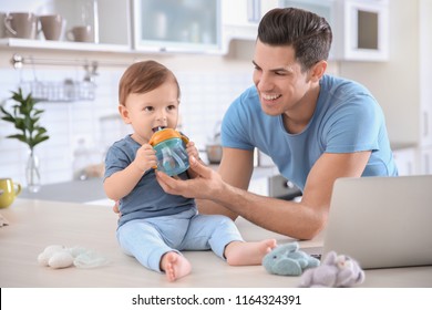 Young Dad Giving Water To His Little Son At Home