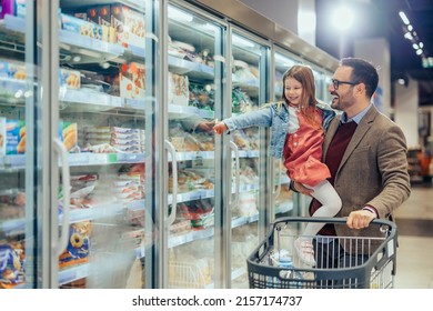 A young dad and his daughter are buying frozen pasta in the supermarket - Shutterstock ID 2157174737