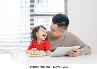 Young Dad And His Daughter Eating Pizza And Using Ipad.