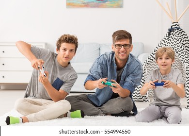 Young Dad And His Two Sons Playing Video Games 