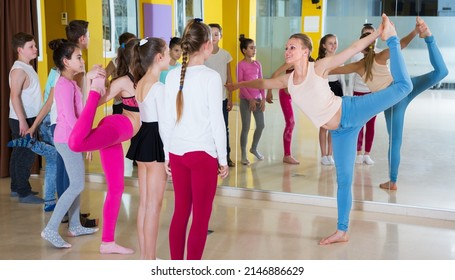 Young dance teacher giving children dance class, showing movements in choreography school - Powered by Shutterstock