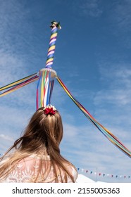 A young dancer looking at the pole with colored ribbons on a traditional English Maypole dancing day