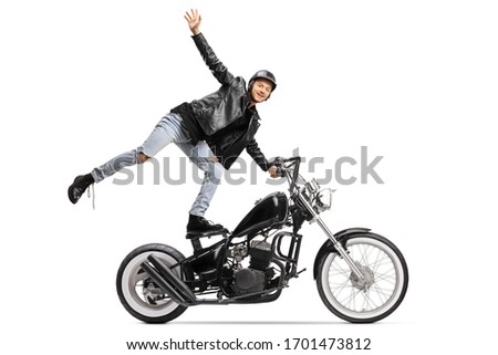 Young daredevil standing on the seat and riding a chopper motorbike isolated on white background