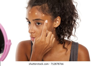 A Young Dark Skinned Woman Applies A Liqud Foundation On Her Face
