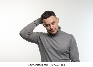A young dark-haired man with a small beard looks in front of him with mockery and slight disappointment. Light background. One person, isolated. - Shutterstock ID 2079634168