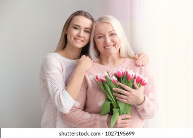 Young Daughter And Mother With Bouquet Of Flowers At Home