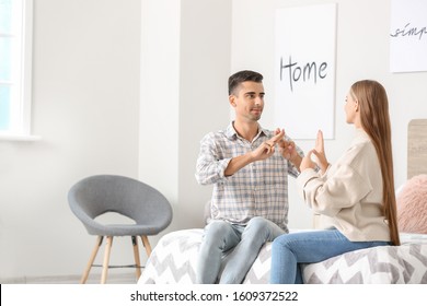 Young deaf mute couple using sign language at home - Shutterstock ID 1609372522