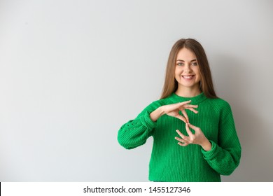 Young Deaf Mute Woman Using Sign Language On Light Background