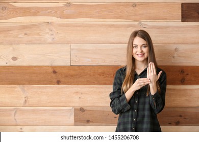 Young Deaf Mute Woman Using Sign Language On Wooden Background