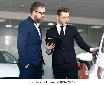 Young Dealer Tells To Buyer About New Car Features. 