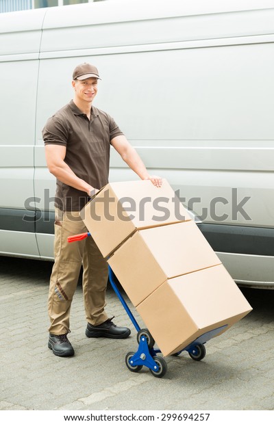 Young\
Delivery Man Holding Trolley With Cardboard\
Boxes