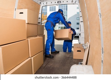 Young delivery men loading cardboard boxes in truck