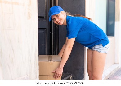 Young Delivery Woman At Outdoors Leaving The Boxes At The Door