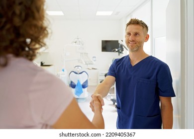 Young Dentist Shaking Hands With The Patient.