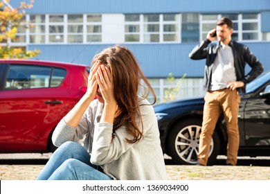 Young Depressed Female Driver After Traffic Accident Sitting On Road