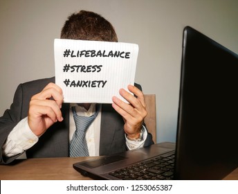 Young Depressed And Frustrated Businessman Working In Stress At Office Computer Desk Holding Notepad With Hashtags Related To Work Stress Life Balance And Business Problem