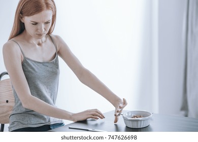 Young Depressed Girl At Table With Food In Bowl. Eating Disorders Concept