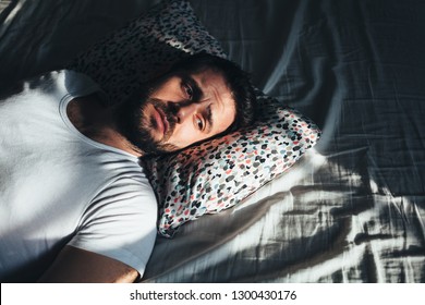 Young depressed man crying in bed