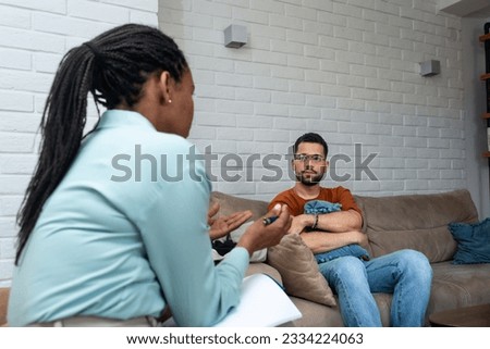 Young depressed man crying talking to mental health counselor during a session in the office. Stressed male at psychotherapy after divorce having emotional damage issue. Relationship difficulties.