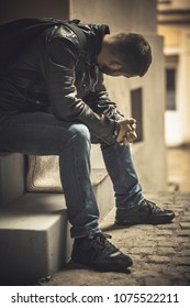 Young Depressed Man Sitting In The Dark Alleyway, Feeling Sadness And Pain