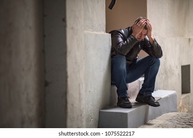 Young Depressed Man Sitting In The Dark Alleyway, Feeling Sadness And Pain